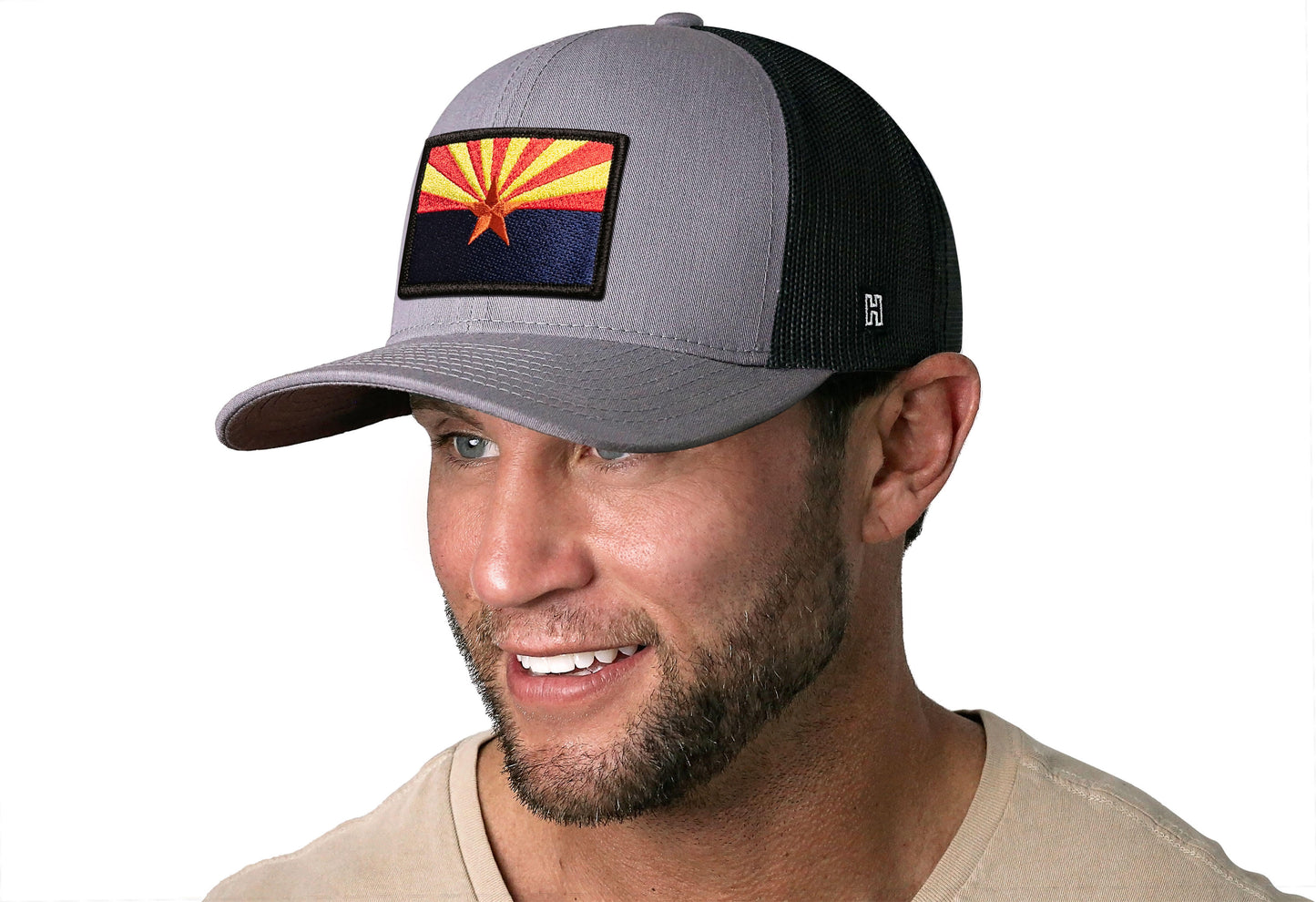 Gray-Black trucker hat worn by a male model viewed from the left side and features a Arizona Flag Embroidered Rectangle Patch displayed on the front panel. The hat has a classic mesh back design and a curved structured bill