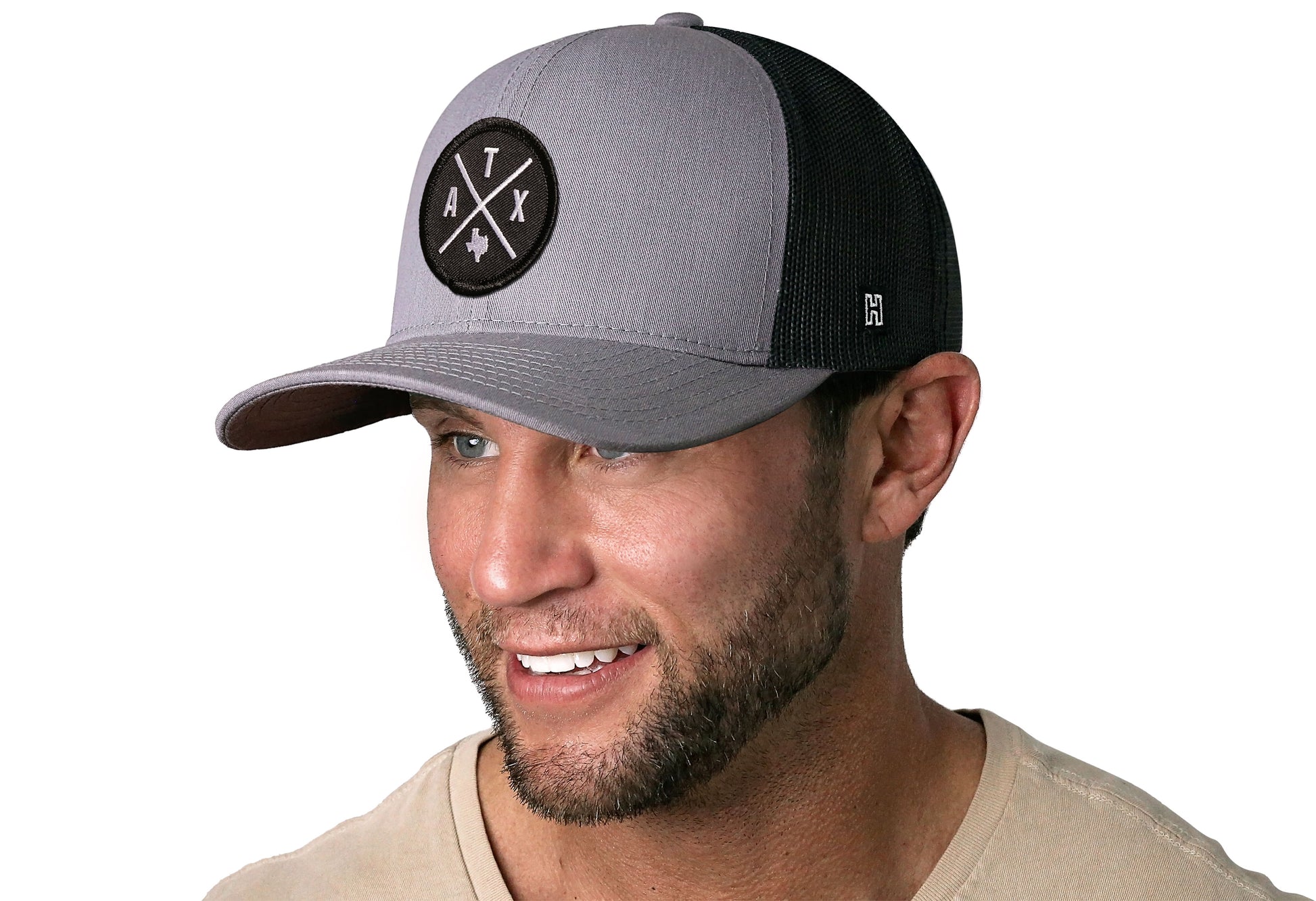 Gray-Black trucker hat worn by a male model viewed from the left side and features a Austin Gray-Black ATX Embroidered X Patch displayed on the front panel. The hat has a classic mesh back design and a curved structured bill