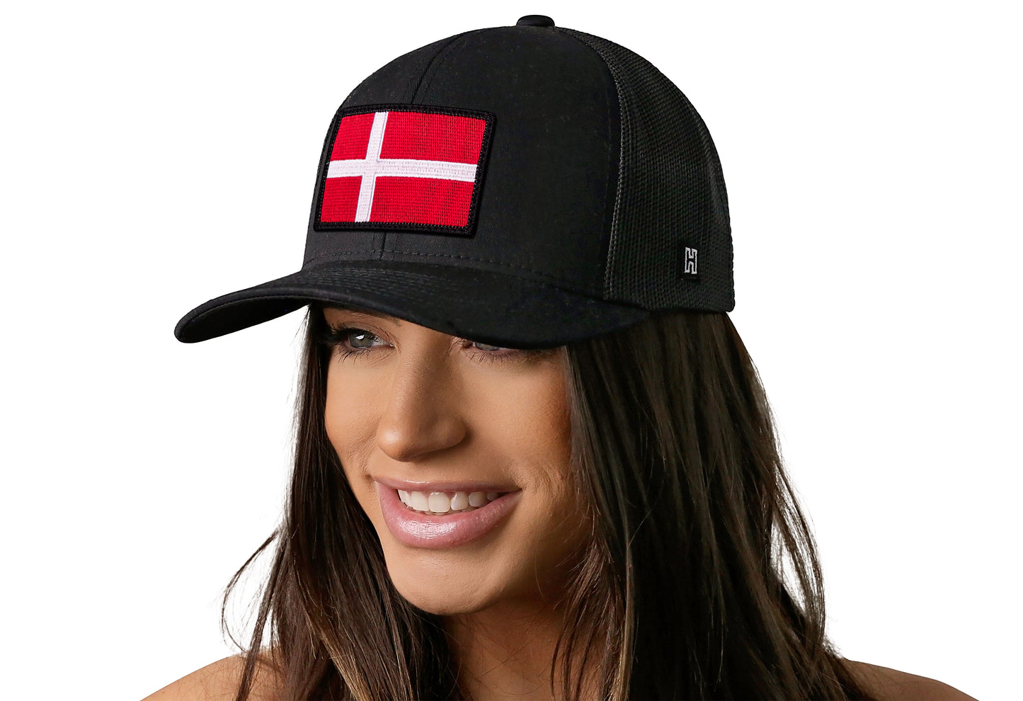 Black trucker hat worn by a female model viewed from the left side and features a Danish Flag Embroidered Rectangle Patch displayed on the front panel. The hat has a classic mesh back design and a curved structured bill