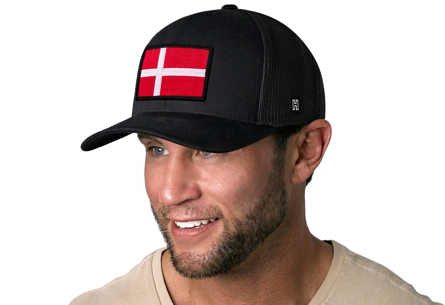 Black trucker hat worn by a male model viewed from the left side and features a Danish Flag Embroidered Rectangle Patch displayed on the front panel. The hat has a classic mesh back design and a curved structured bill