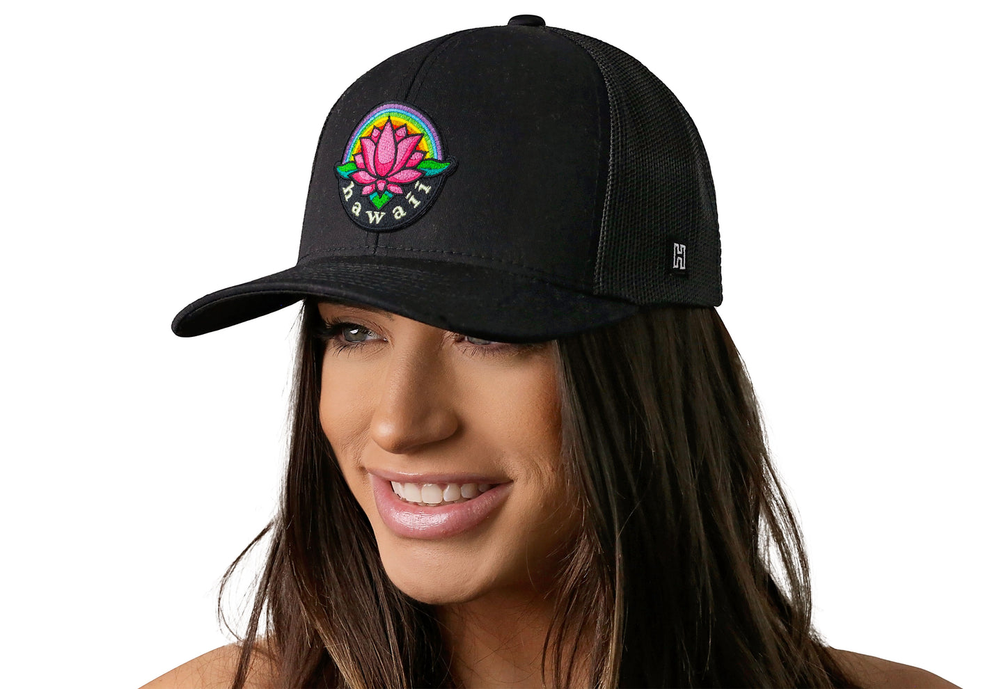 Black trucker hat worn by a female model viewed from the left side and features a Hawaii Flower Embroidered Patch displayed on the front panel. The hat has a classic mesh back design and a curved structured bill