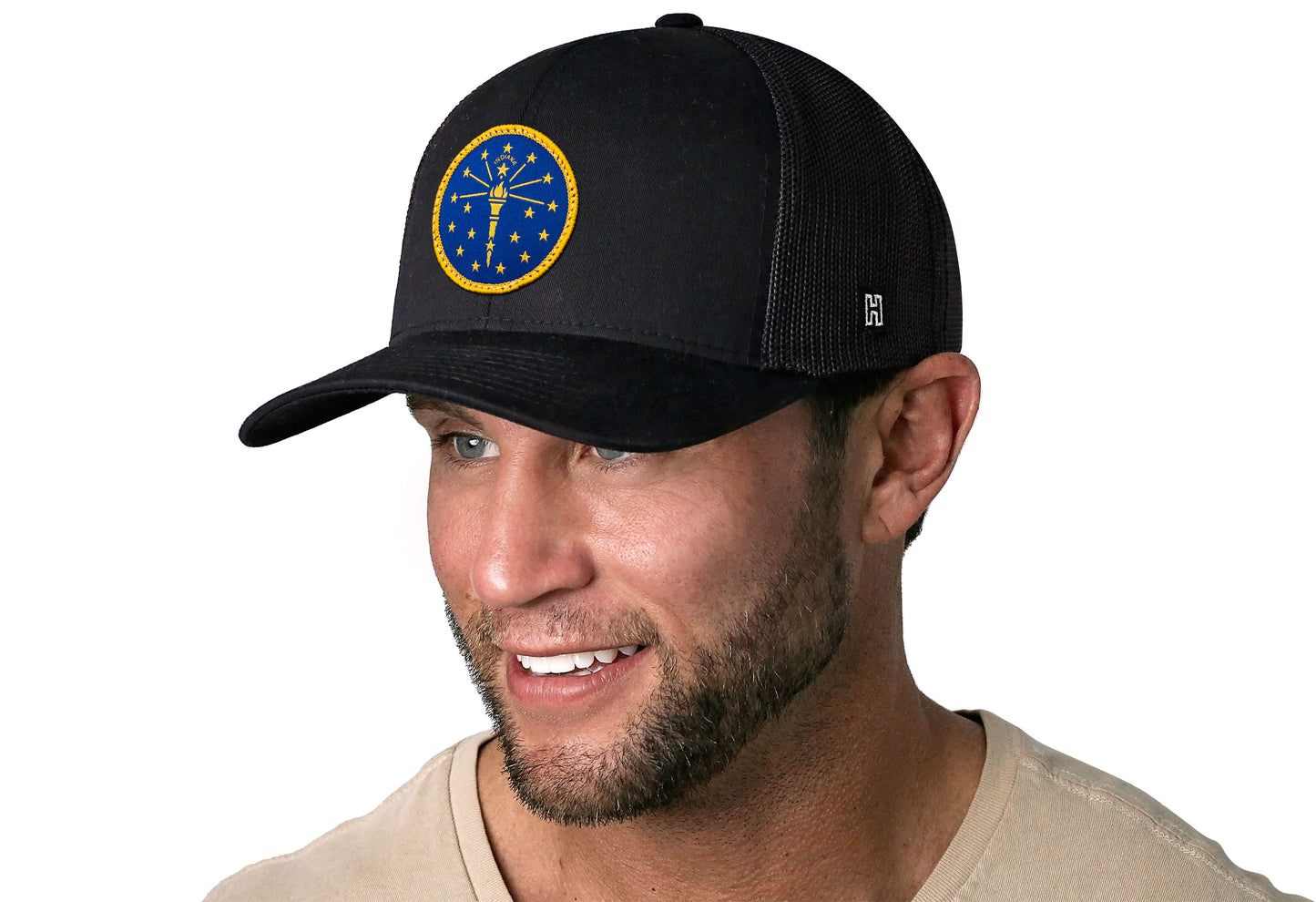 Black trucker hat worn by a male model viewed from the left side and features a Indiana Flag Embroidered Circle Patch displayed on the front panel. The hat has a classic mesh back design and a curved structured bill