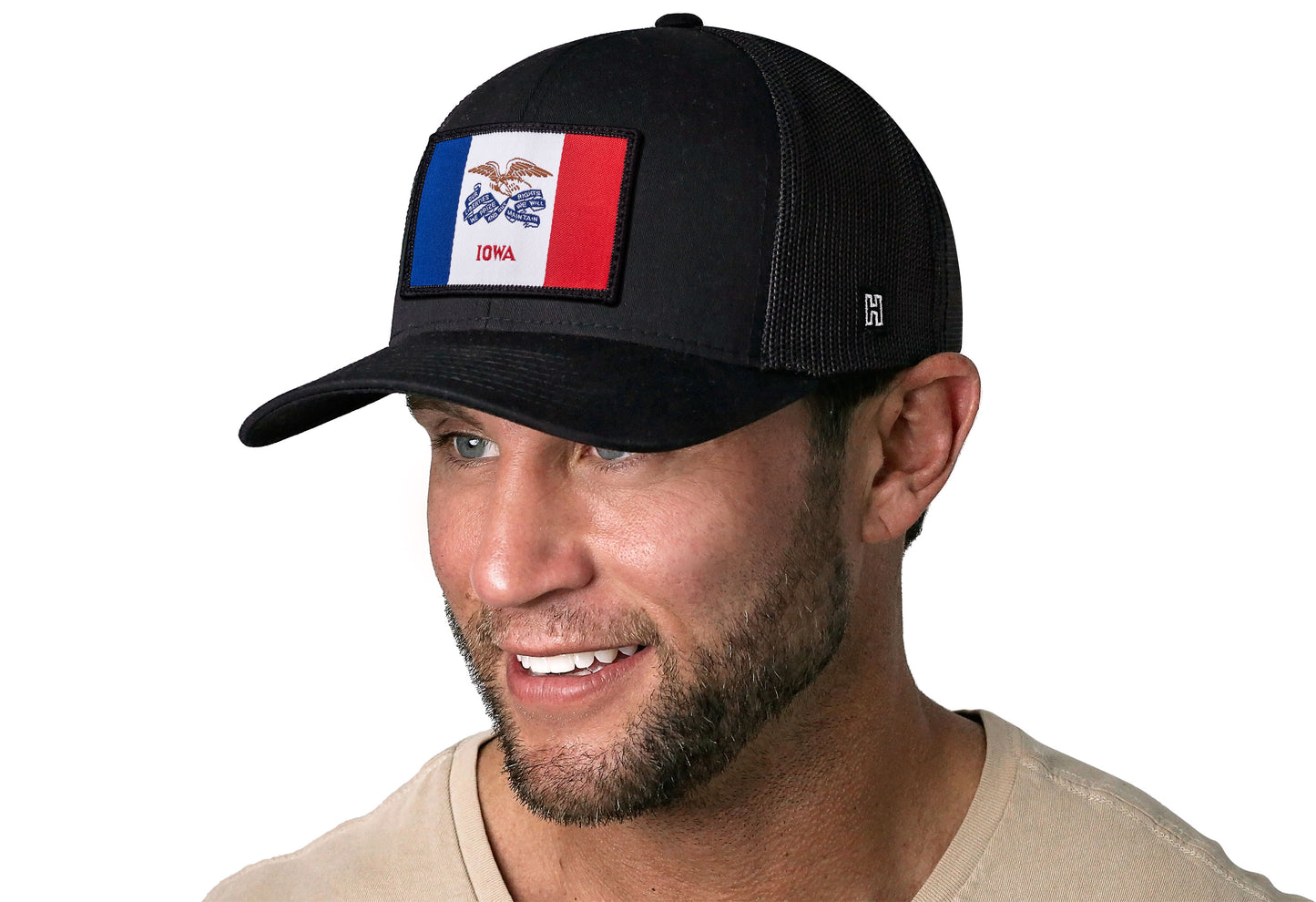 Black trucker hat worn by a male model viewed from the left side and features a Iowa Woven Rectangle Patch displayed on the front panel. The hat has a classic mesh back design and a curved structured bill