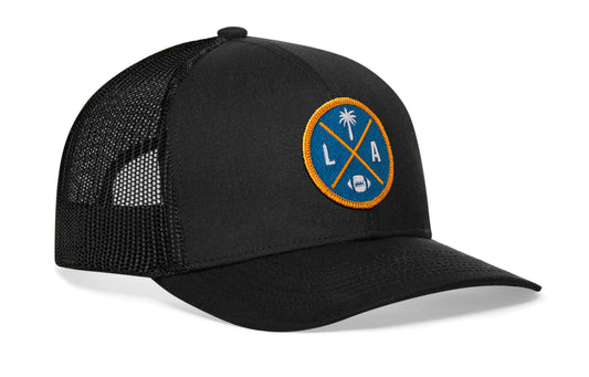 black trucker hat viewed from the right side, showcasing a LA Football embroidered X patch in gold and light blue prominently displayed on the front
