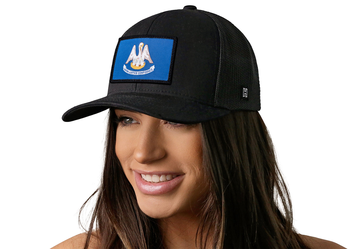 Black trucker hat worn by a female model viewed from the left side and features a Louisiana Woven Rectangle Patch displayed on the front panel. The hat has a classic mesh back design and a curved structured bill