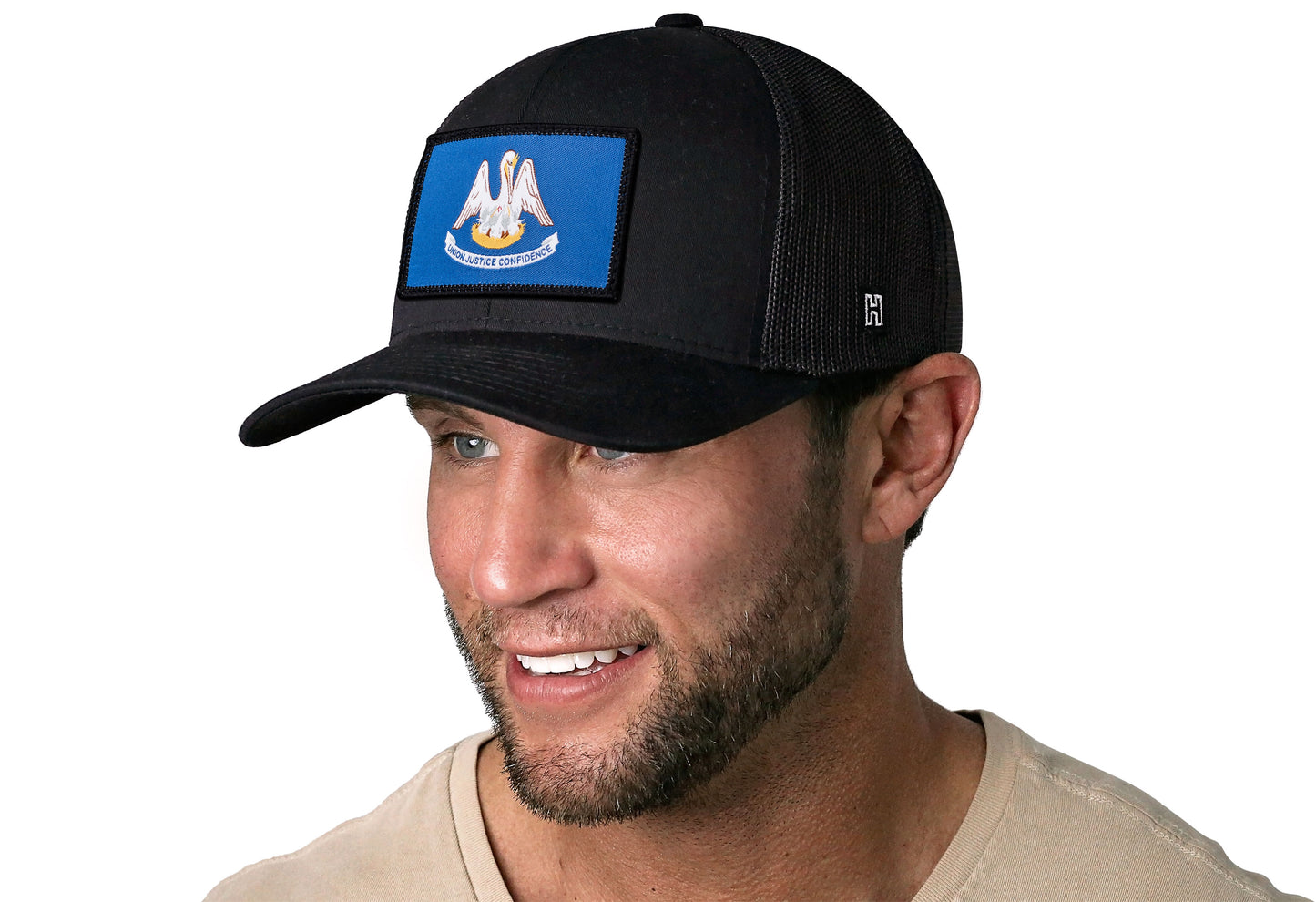 Black trucker hat worn by a male model viewed from the left side and features a Louisiana Woven Rectangle Patch displayed on the front panel. The hat has a classic mesh back design and a curved structured bill