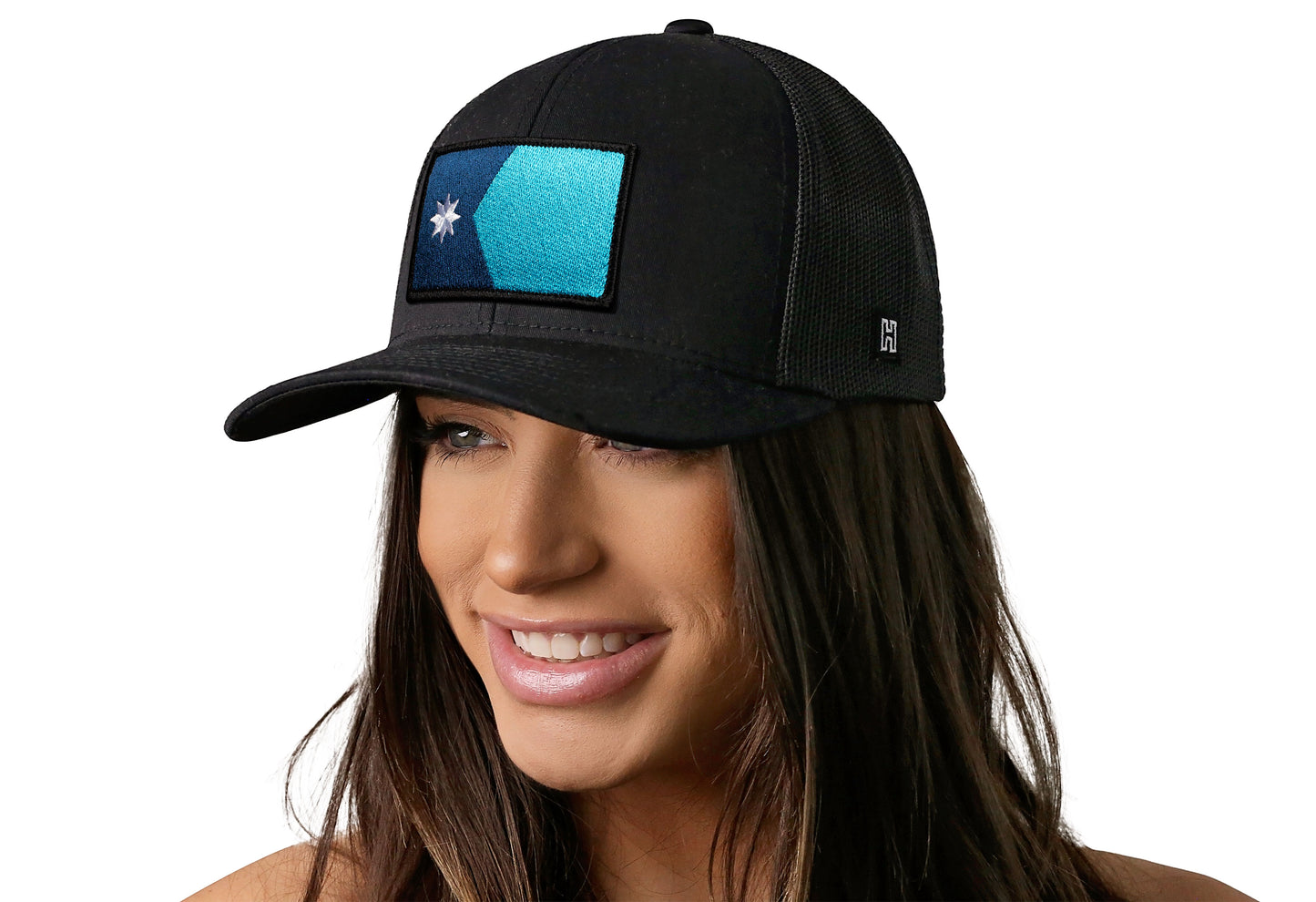 Black trucker hat worn by a female model viewed from the left side and features a Minnesota Flag Embroidered Rectangle Patch displayed on the front panel. The hat has a classic mesh back design and a curved structured bill