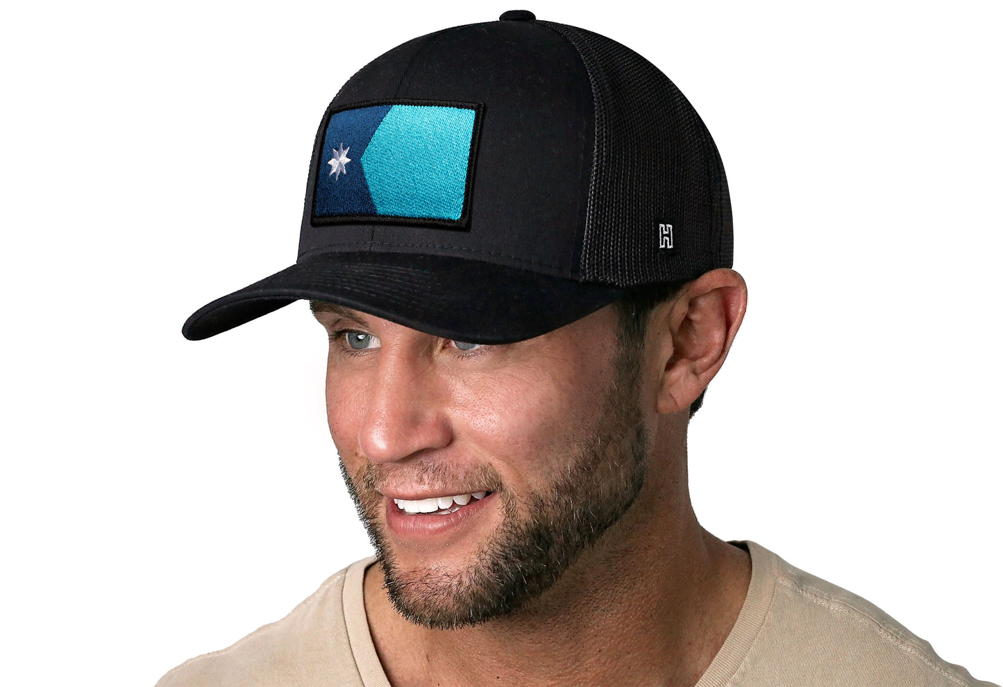 Black trucker hat worn by a male model viewed from the left side and features a Minnesota Flag Embroidered Rectangle Patch displayed on the front panel. The hat has a classic mesh back design and a curved structured bill