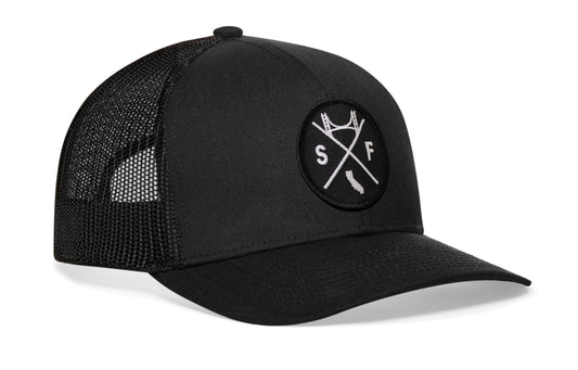 Black trucker hat viewed from the right side, showcasing a San Francisco SF X Embroidered Circle Patch prominently displayed on the front