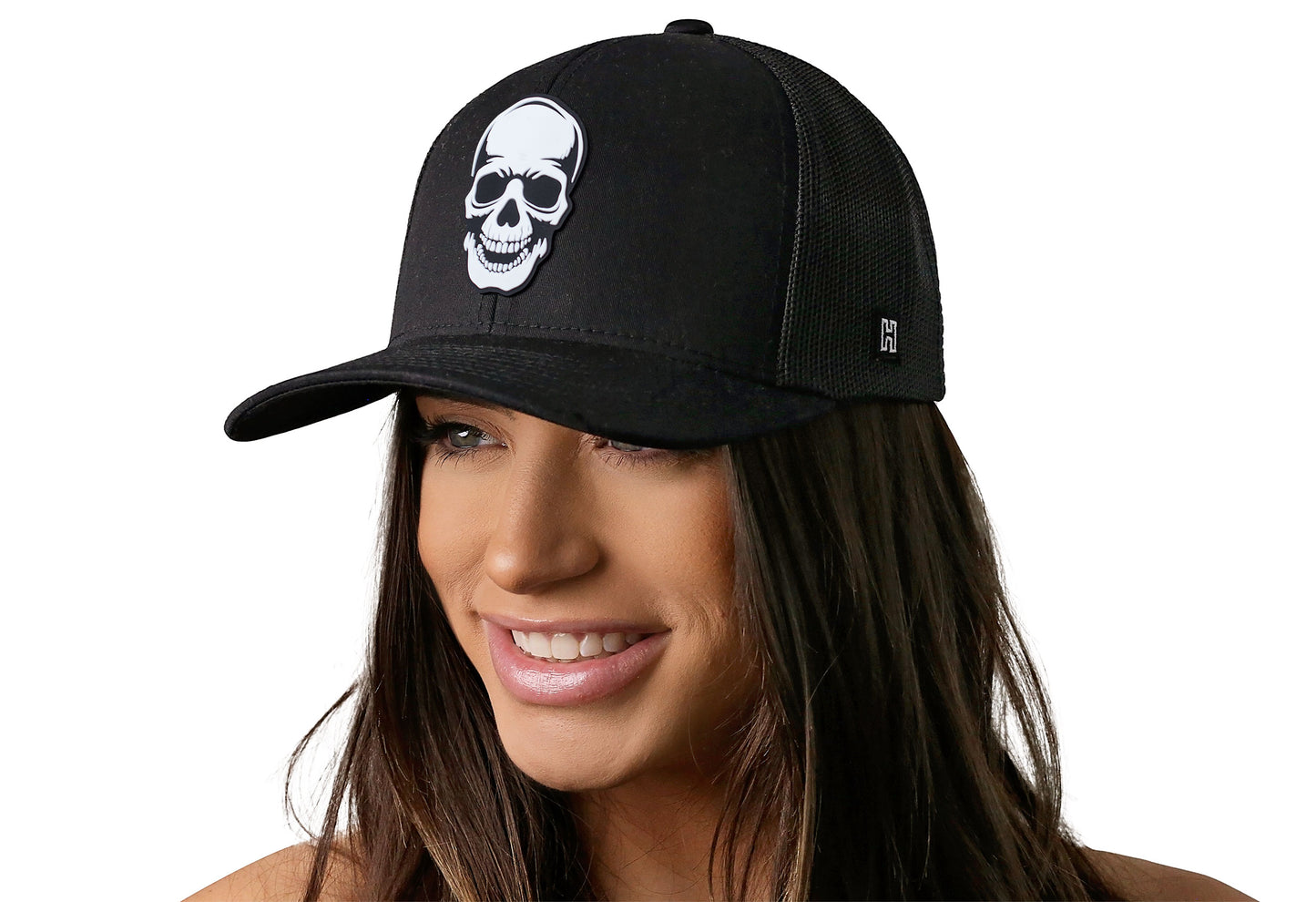Black trucker hat worn by a female model viewed from the left side and features a Skull Black Rubber displayed on the front panel. The hat has a classic mesh back design and a curved structured bill