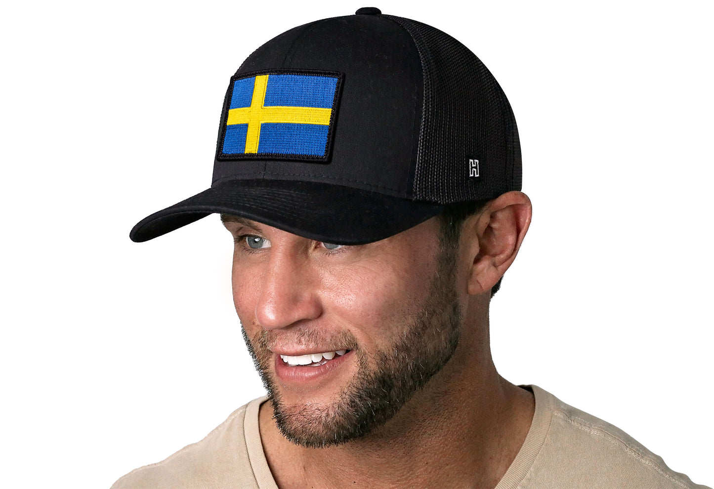 Black trucker hat worn by a male model viewed from the left side and features a Swedish Flag Embroidered Rectangle Patch displayed on the front panel. The hat has a classic mesh back design and a curved structured bill