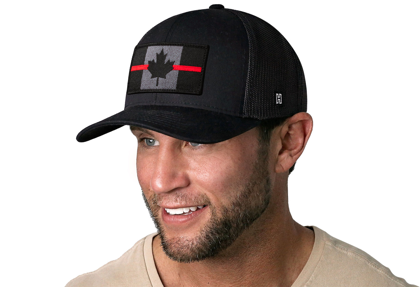 black trucker hat worn by a male model viewed from the left side and features a Thin Red Line Tactical Canadian Flag Embroidered Rectangle Patch displayed on the front panel. The hat has a classic mesh back design and a curved structured bill