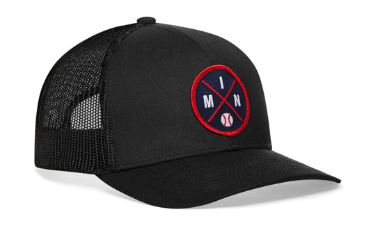 black trucker hat viewed from the right side, showcasing a navy and red baseball embroidered X patch prominently displayed on the front