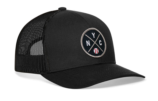 black trucker hat viewed from the right side, showcasing a navy and gray baseball embroidered X patch prominently displayed on the front