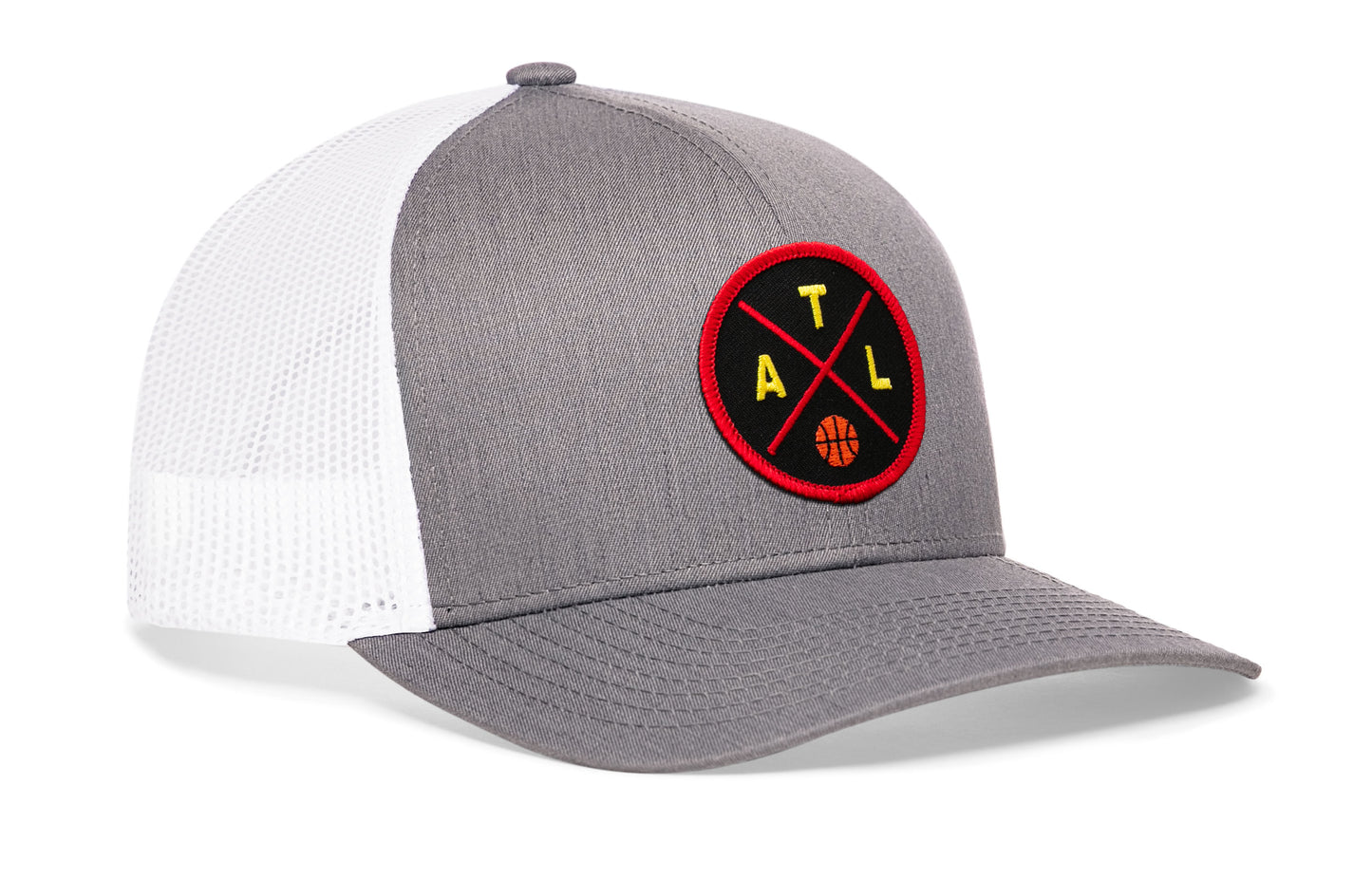gray-white trucker hat viewed from the right side, showcasing a bold red and black embroidered X patch prominently displayed on the front