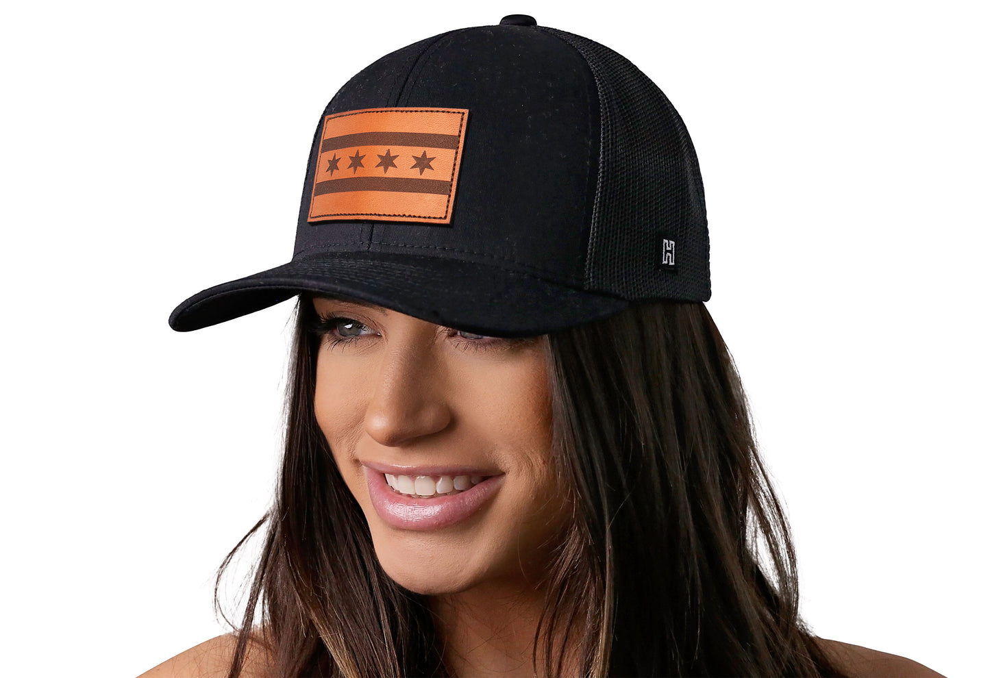 Black trucker hat worn by a female model viewed from the left side and features a Chicago Flag Leather Rectangle Patch displayed on the front panel. The hat has a classic mesh back design and a curved structured bill