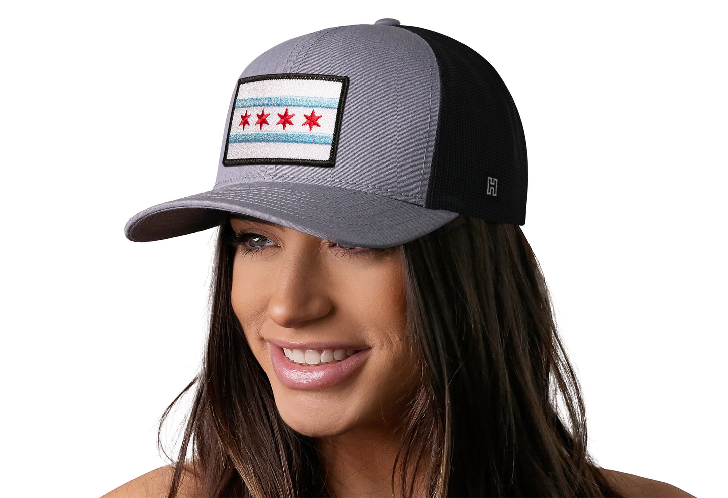 Gray-Black trucker hat worn by a female model viewed from the left side and features a Chicago Flag Embroidered Rectangle Patch displayed on the front panel. The hat has a classic mesh back design and a curved structured bill