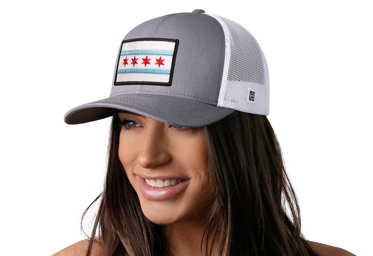 Gray-White trucker hat worn by a female model viewed from the left side and features a Chicago Flag Embroidered Rectangle Patch displayed on the front panel. The hat has a classic mesh back design and a curved structured bill