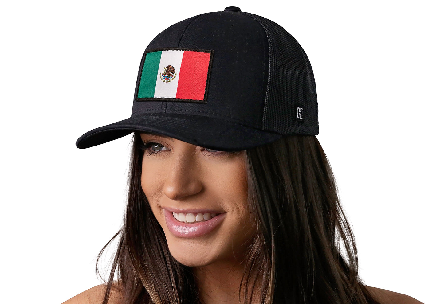Black trucker hat worn by a female model viewed from the left side and features a Mexican Flag Woven Rectangle Patch displayed on the front panel. The hat has a classic mesh back design and a curved structured bill