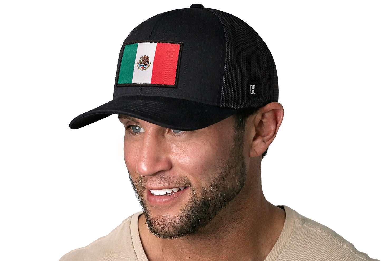 Black trucker hat worn by a male model viewed from the left side and features a Mexican Flag Woven Rectangle Patch displayed on the front panel. The hat has a classic mesh back design and a curved structured bill