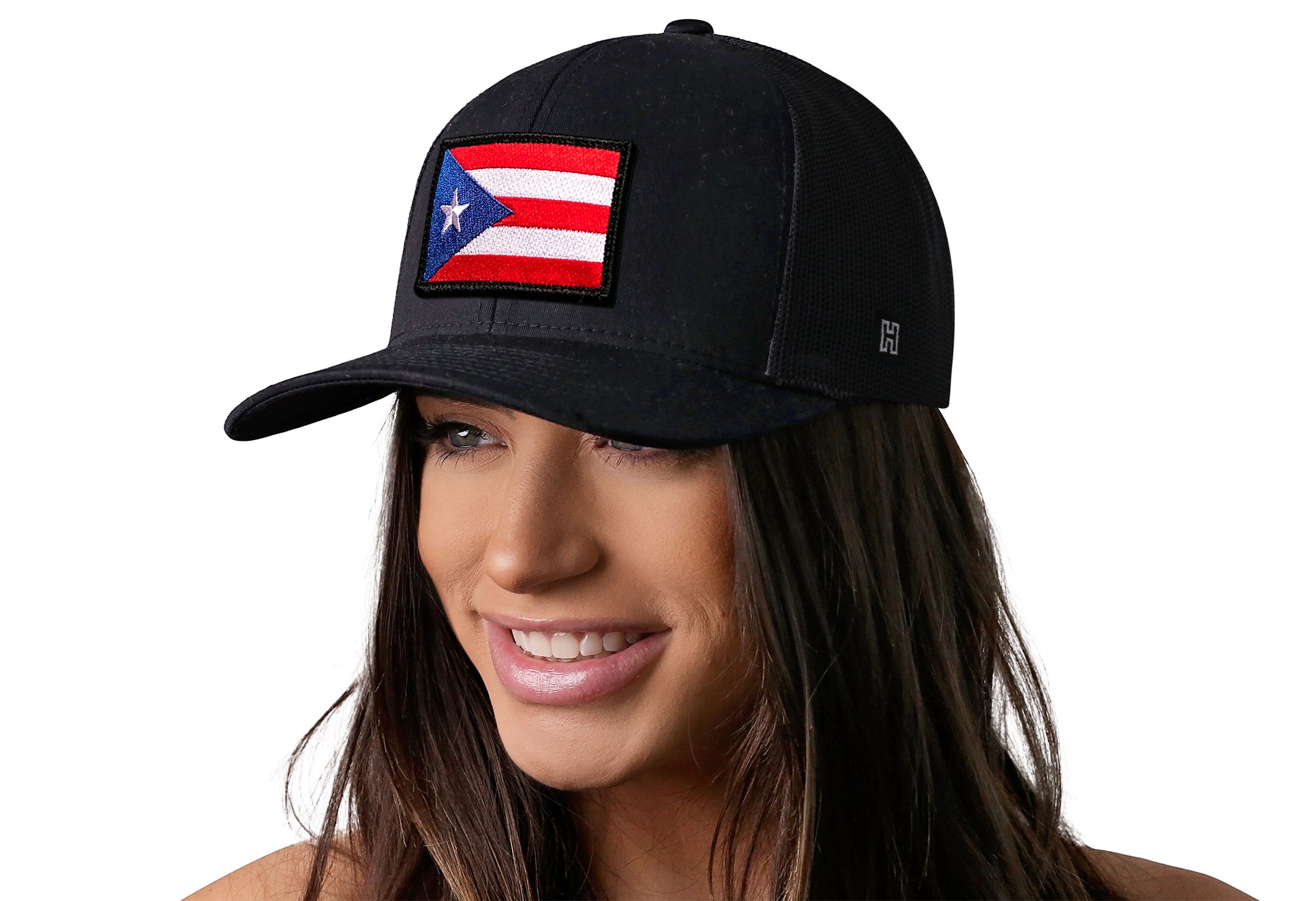 Black trucker hat worn by a female model viewed from the left side and features a Puerto Rico Flag Embroidered Flag Patch displayed on the front panel. The hat has a classic mesh back design and a curved structured bill