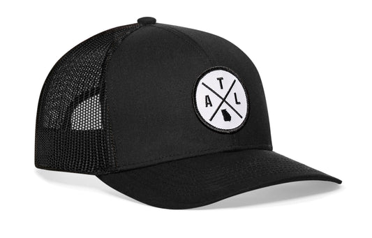 Black trucker hat viewed from the right side, showcasing a Atlanta ATL X Embroidered White Circle Patch prominently displayed on the front