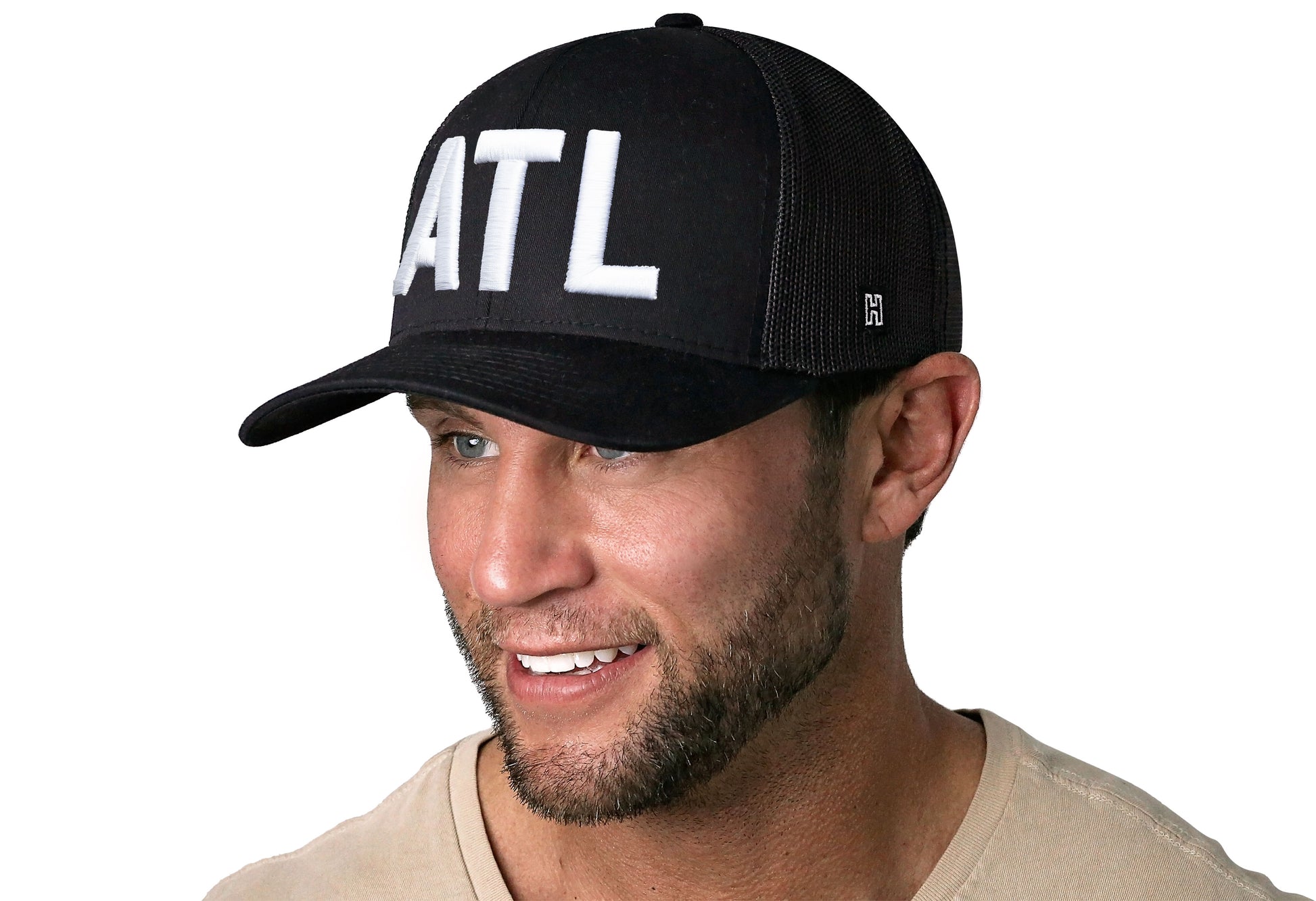 Black trucker hat worn by a male model viewed from the left side and features a ATL 3-D Puff Direct Embroidery displayed on the front panel. The hat has a classic mesh back design and a curved structured bill