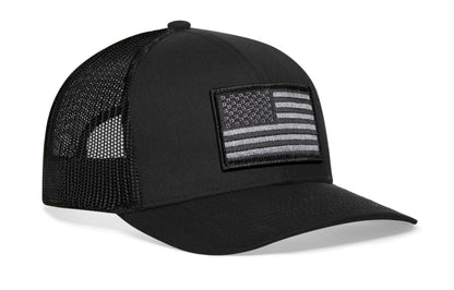 Black trucker hat viewed from the right side, showcasing a American Flag Embroidered Rectangle Patch prominently displayed on the front