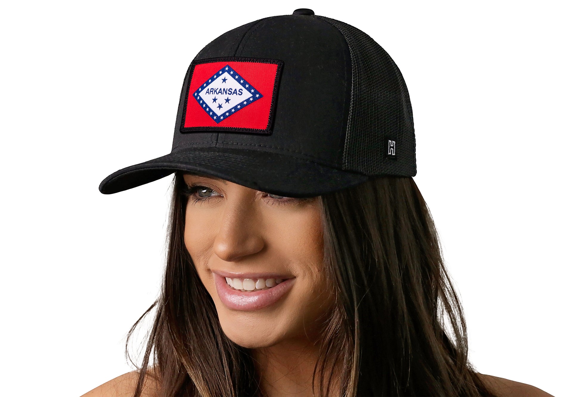 Black trucker hat worn by a female model viewed from the left side and features a Arkansas Flag Embroidered Rectangle Patch displayed on the front panel. The hat has a classic mesh back design and a curved structured bill