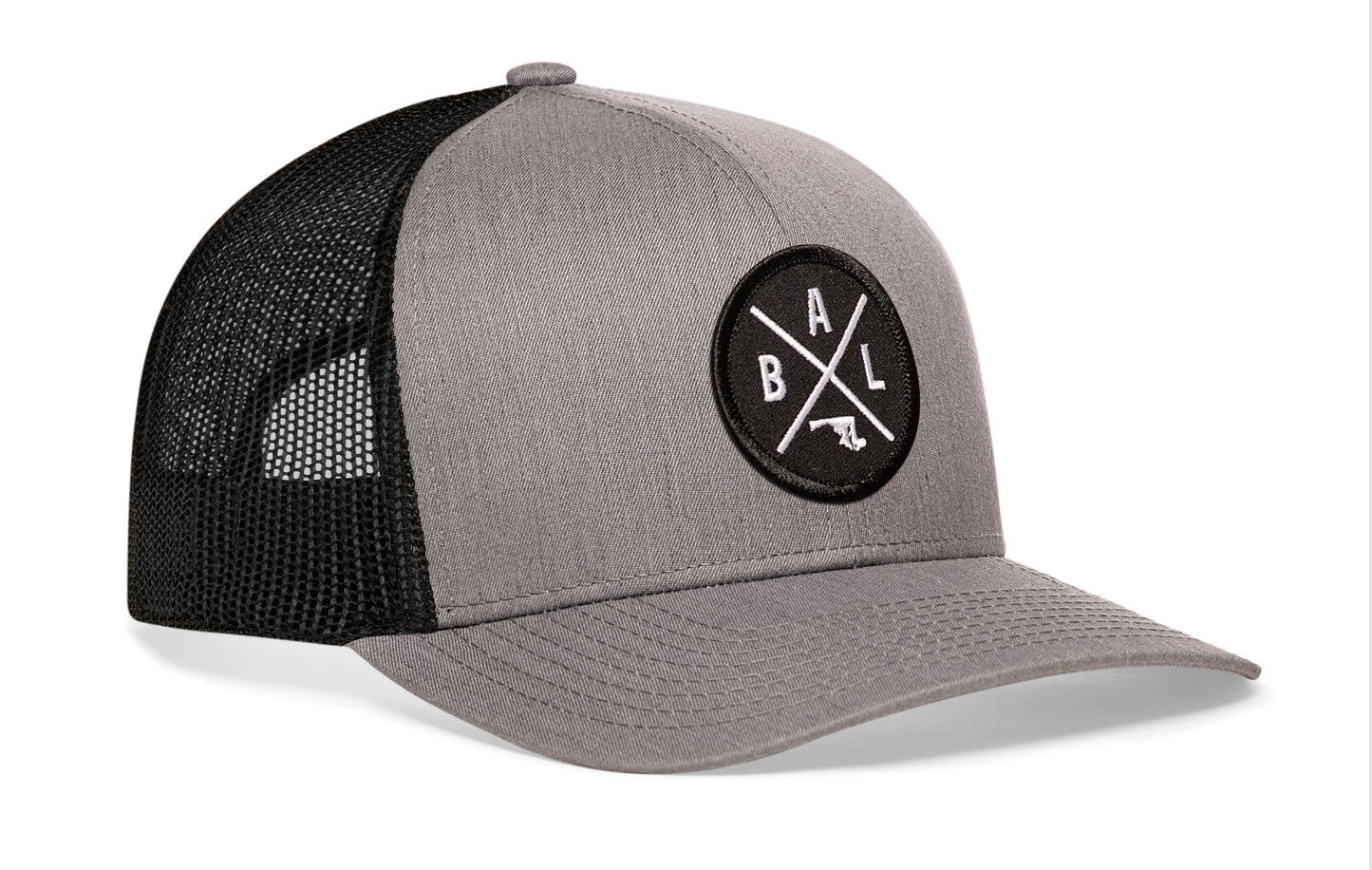 Gray-Black trucker hat viewed from the right side, showcasing a Baltimore BAL X Embroidered Circle Patch prominently displayed on the front