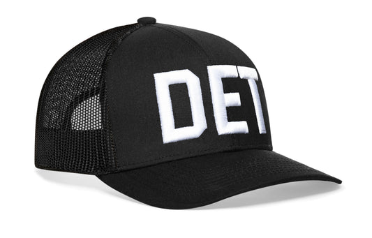 Black trucker hat viewed from the right side, showcasing a DET 3-D Puff Direct Embroidery prominently displayed on the front
