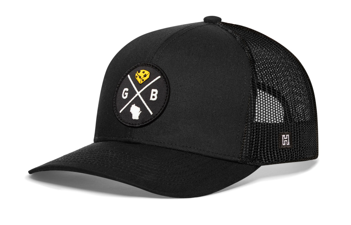 Green Bay Trucker Hat, black snapback showing Haka brandmark on left side of cap.