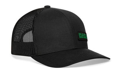 Black trucker hat viewed from the right side, showcasing a HAKA Rectangle Rubber Patch prominently displayed on the front