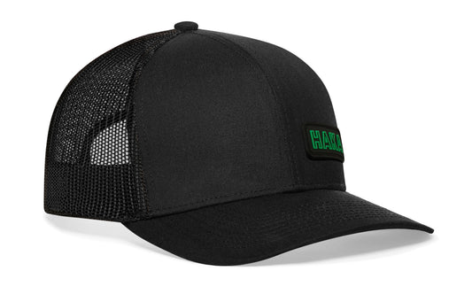 Black trucker hat viewed from the right side, showcasing a HAKA Rectangle Rubber Patch prominently displayed on the front