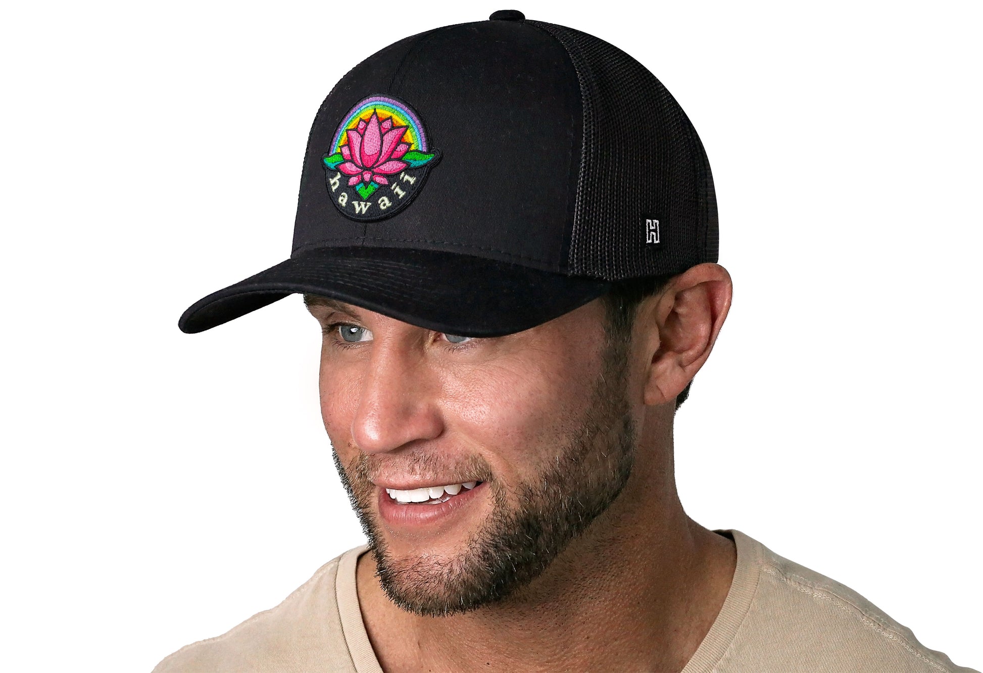 Black trucker hat worn by a male model viewed from the left side and features a Hawaii Flower Embroidered Patch displayed on the front panel. The hat has a classic mesh back design and a curved structured bill