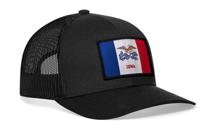 Black trucker hat viewed from the right side, showcasing a Iowa Woven Rectangle Patch prominently displayed on the front