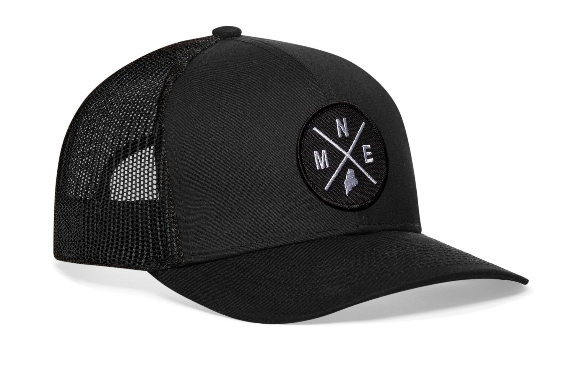 Black trucker hat viewed from the right side, showcasing a Maine MNE X Embroidered Circle Patch prominently displayed on the front