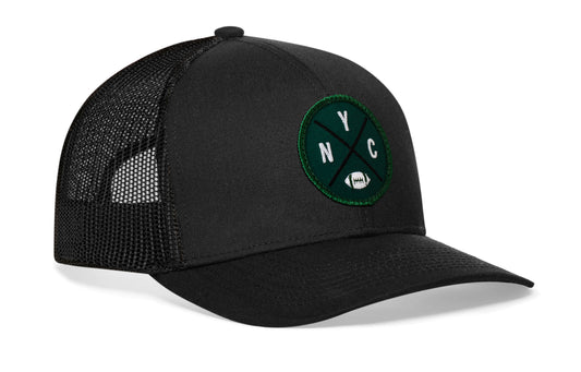 black trucker hat viewed from the right side, showcasing a NYC Football embroidered X patch in green and white prominently displayed on the front
