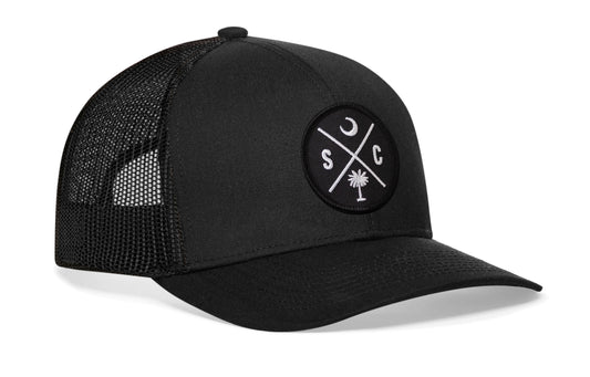 Black trucker hat viewed from the right side, showcasing a South Carolina SC Embroidered X Patch prominently displayed on the front