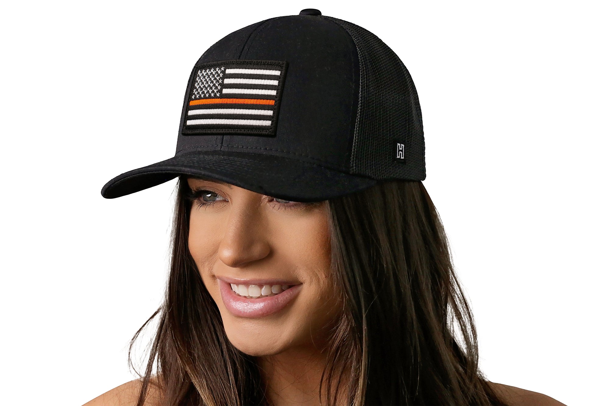 Black trucker hat worn by a female model viewed from the left side and features a Thin Orange Line Flag patch prominently displayed on the front panel. The hat has a classic mesh back design and a curved structured bill.