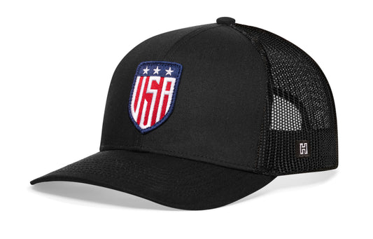 USA Shield Trucker Hat, black snapback showing Haka brandmark on left side of cap.