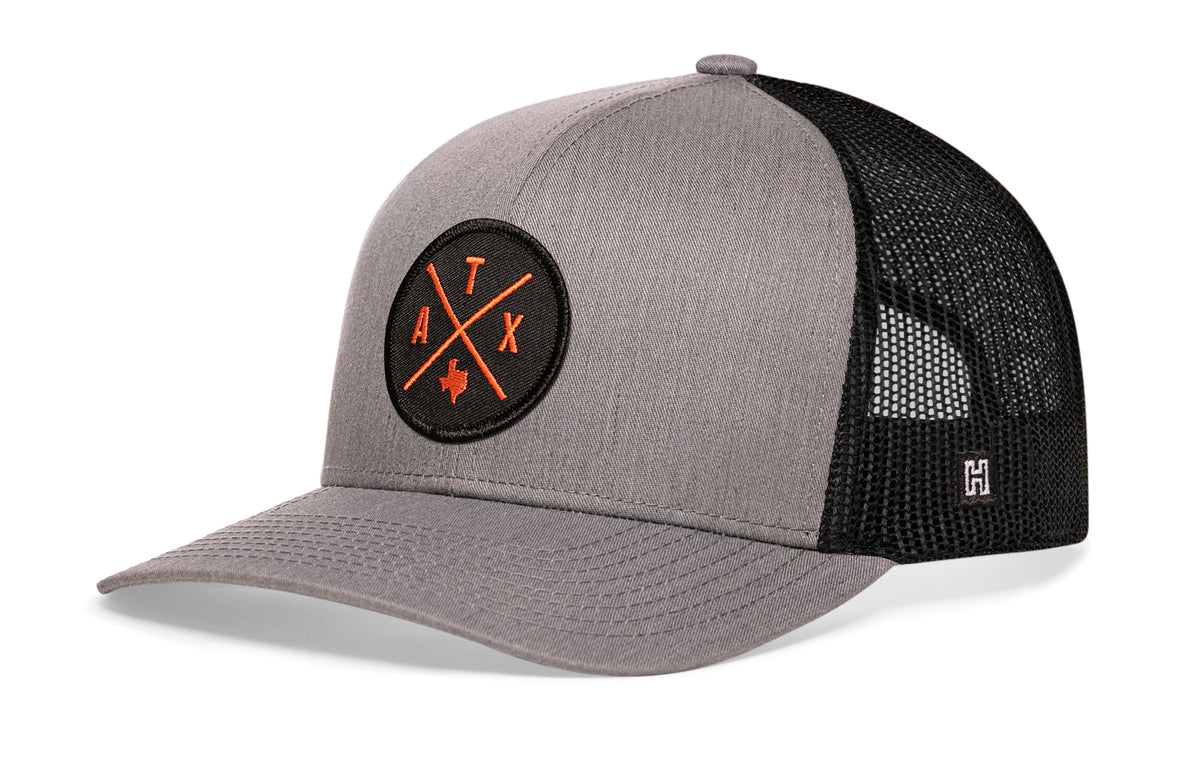 Austin Trucker Hat, gray-black snapback showing Haka brandmark on left side of cap.