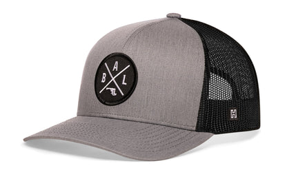 Baltimore Trucker Hat, gray-black snapback showing Haka brandmark on left side of cap.