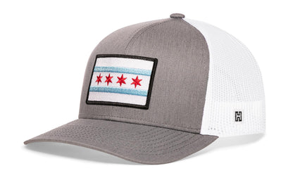 Chicago Trucker Hat, gray-white snapback showing Haka brandmark on left side of cap.