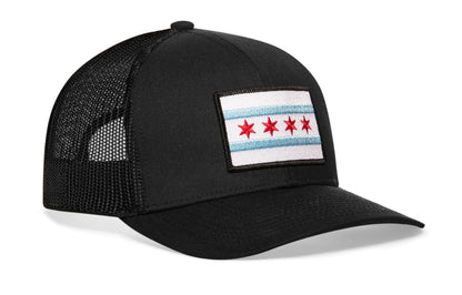 black trucker hat viewed from the right side, showcasing a bold red and light blue embroidered flag patch prominently displayed on the front