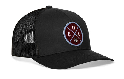 black trucker hat viewed from the right side, showcasing a bold burgundy and blue embroidered X patch prominently displayed on the front