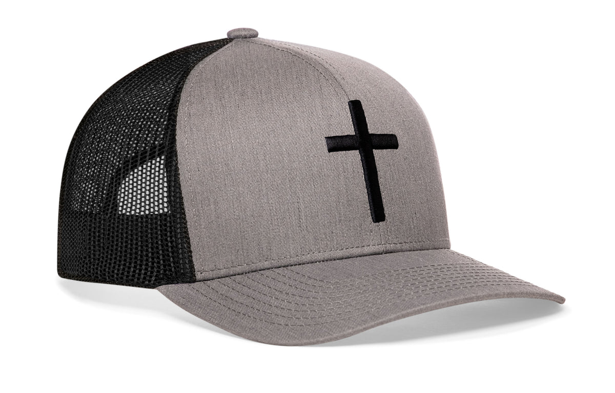 gray-black trucker hat viewed from the right side, showcasing a bold cross bold white 3D embroidery prominently displayed on the front