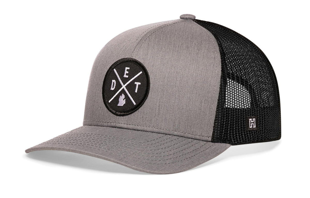 Detroit Trucker Hat, gray-black snapback showing Haka brandmark on left side of cap.