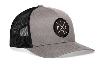 gray-black trucker hat viewed from the right side, showcasing a bold black and white embroidered X patch prominently displayed on the front