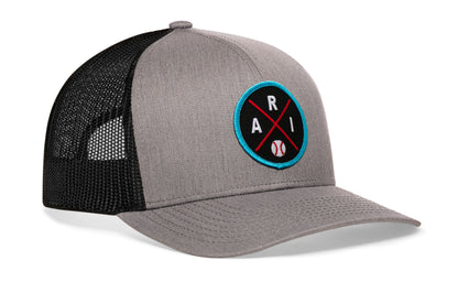 gray-black trucker hat viewed from the right side, showcasing a bold black, red and columbia blue embroidered X patch prominently displayed on the front